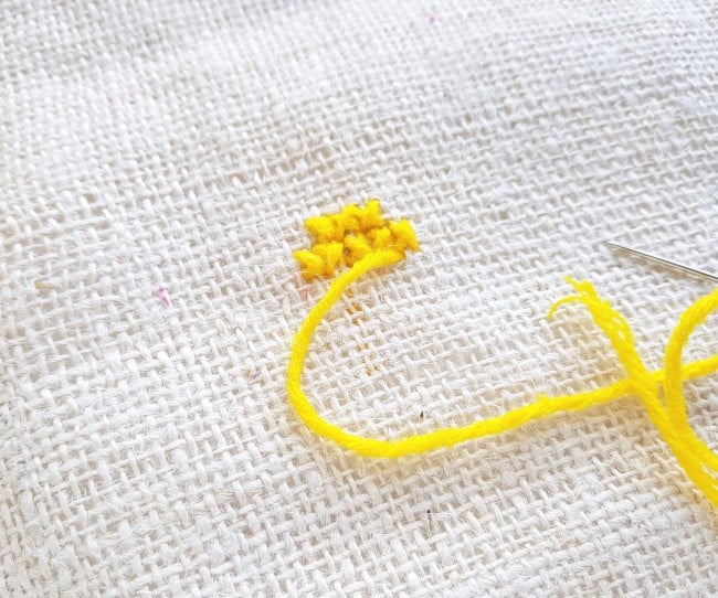 Easy Cross Stitch Pattern - first two rows of yellow yarn cross stitch on burlap fabric