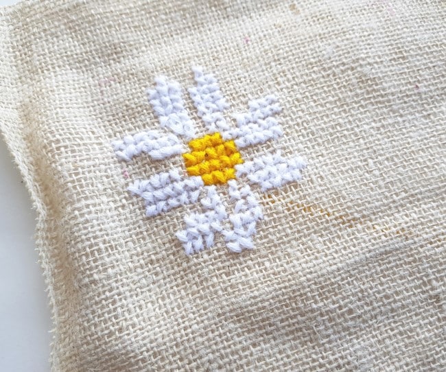 Easy Cross Stitch Pattern - one daisy complete on the burlap fabric.