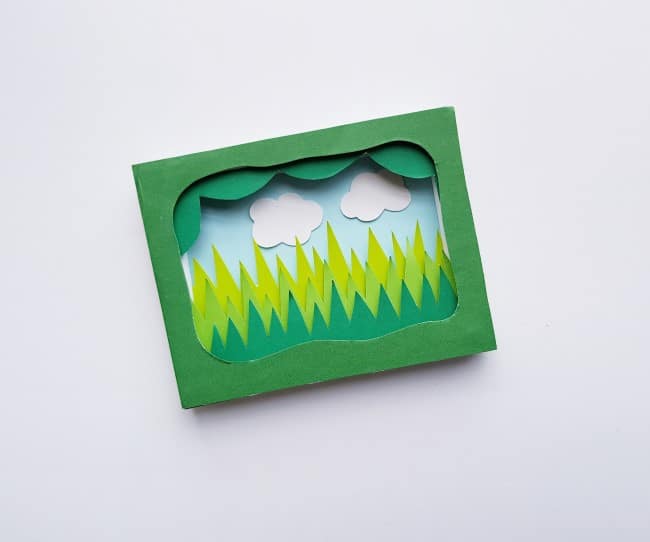3D garden paper craft - blue background and white cut out clouds added to frame