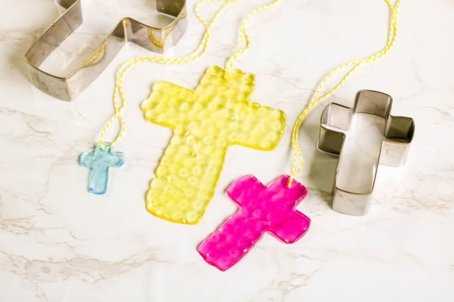 cross suncatcher melted bead idea - three suncatchers: blue, yellow, and pink, with cross cookie cutters also in image