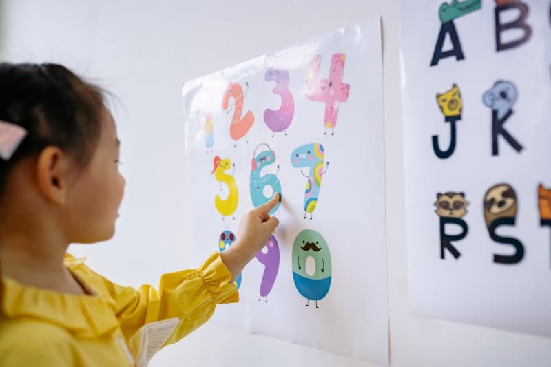 learn numbers - little girl pointing at numbers on a poster